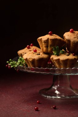 Koyu bir arka planda cam tatlı standında yaban mersinli kırmızı kekler.