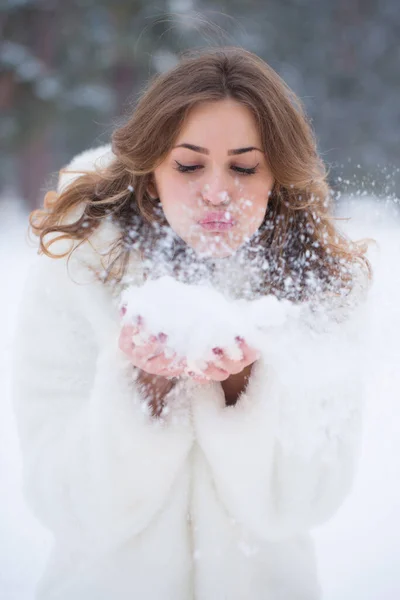 冬の雪の中で遊ぶ白い毛皮のコートの若い女性の肖像画 — ストック写真
