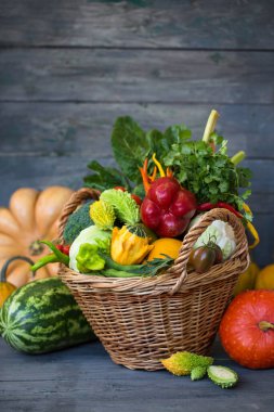 Ahşap bir arka planda çeşitli sebze ve meyvelerden oluşan büyük bir sepet.