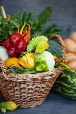 Ahşap bir arka planda çeşitli sebze ve meyvelerden oluşan büyük bir sepet.