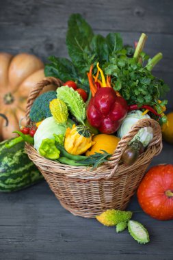 Ahşap bir arka planda çeşitli sebze ve meyvelerden oluşan büyük bir sepet.