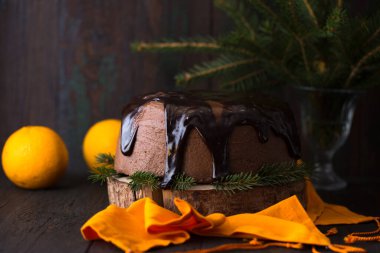 Koyu arkaplanda çikolata kremalı ve portakallı Noel pastası.