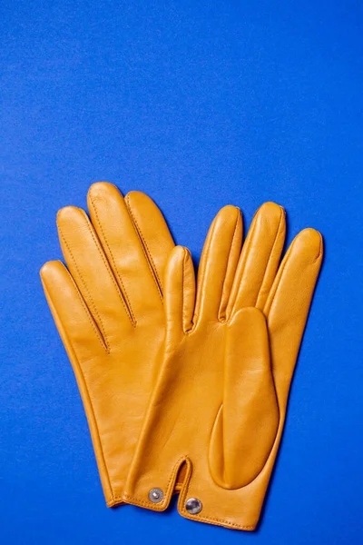 Yellow women\'s gloves made of soft genuine leather on a blue background