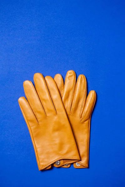 Yellow women\'s gloves made of soft genuine leather on a blue background