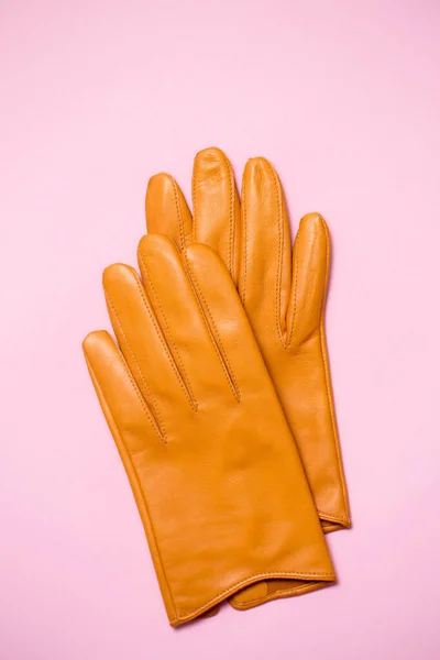 Yellow women\'s gloves made of soft genuine leather on a pink background