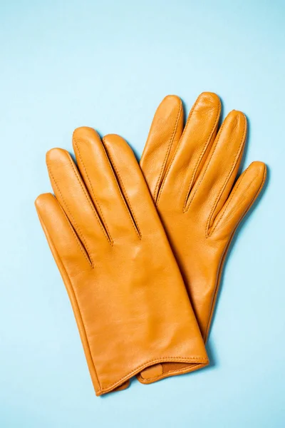 Yellow women\'s gloves made of soft genuine leather on a light blue background