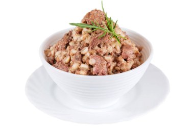 Canned pearl porridge with meat and arugula in a bowl isolated on white background