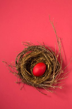 Big red eggs in a small nest on a pink background. Color Viva Magenta 18-1750, in 2023