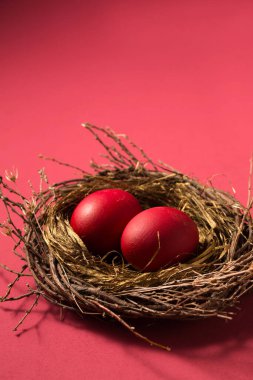 Big red eggs in a small nest on a pink background. Color Viva Magenta 18-1750, in 2023
