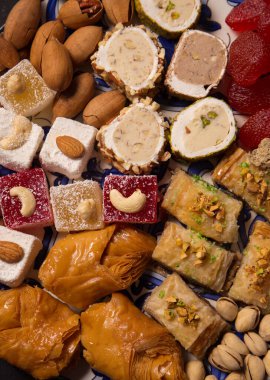 A large plate of various oriental sweets and nuts on a dark background