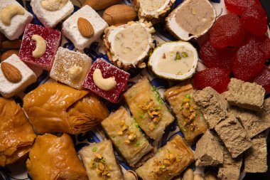 A large plate of various oriental sweets and nuts on a dark background