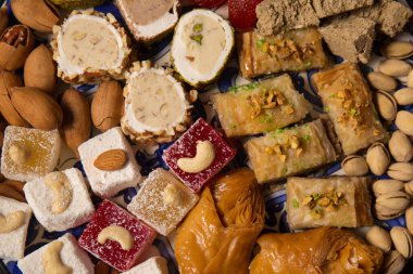A large plate of various oriental sweets and nuts on a dark background