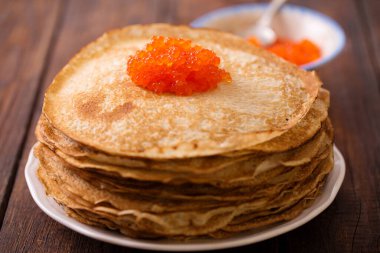 Ahşap zemin üzerinde kırmızı havyar olan bir tabakta leziz ince krep.