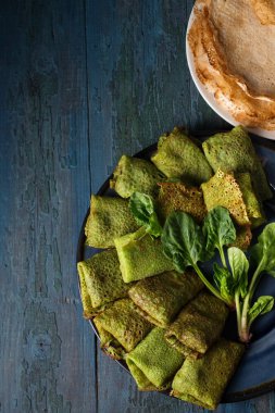 Kırsal bir zeminde ıspanaklı leziz, ince yeşillikli krepler.