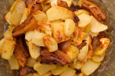 Büyük bir tabakta kızarmış domuz eti dilimlenmiş kızarmış patates.