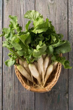 Tahta üzerinde yaprakları olan mor-beyaz tenli taze bahar turpu.