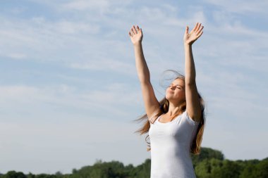 Mutlu, özgür bir kadın kollarını kaldırıp dışarıdaki güneşi selamlıyor.