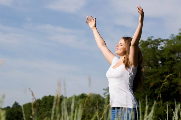 自由的女人高举双臂站在那里 向室外的太阳致敬 — 图库照片