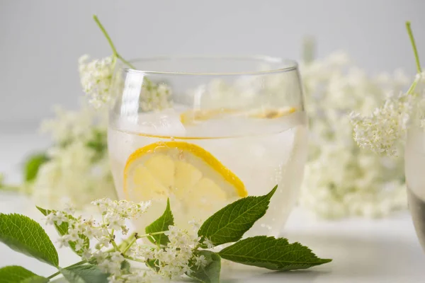 stock image A delicious cold summer drink made of elderflowers and lemon with ice on a light background