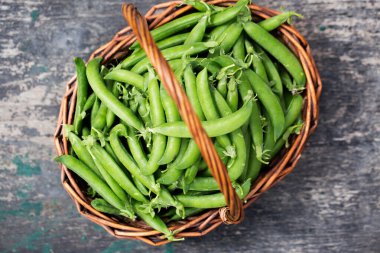 Köy arka planında sepette taze taze bezelyeler.