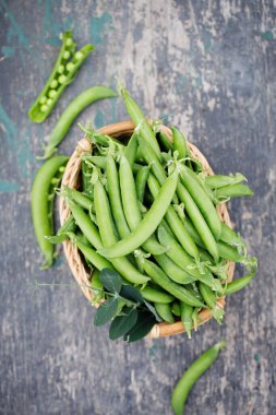 Köy arka planında sepette taze taze bezelyeler.