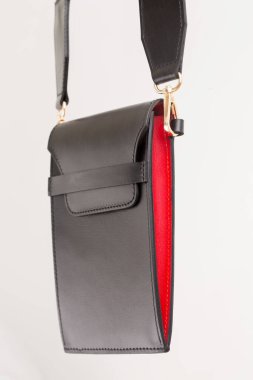 Siyah deriden yapılmış küçük bir akıllı telefon çantası. Beyaz arka planda kırmızı etiketler var.