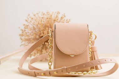 Bej rengi, doğal deri ve altın zincirli küçük bir çanta.
