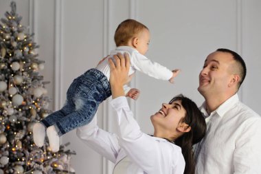 Mutlu genç bir çift ve Noel ağacının yanında küçük bir çocuğu var.