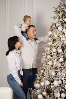 Mutlu genç bir çift ve Noel ağacının yanında küçük bir çocuğu var.