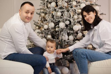 Mutlu genç bir çift ve Noel ağacının yanında küçük bir çocuğu var.