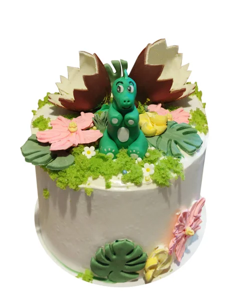 Cream cake decorated with a dragon figurine and chocolate eggs, isolated on a white background