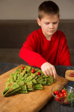 Noel yemeği panosu. Domates ve sosisle süslenmiş ıspanaklı krepten yapılmış Noel ağacı..