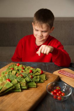 Noel yemeği panosu. Domates ve sosisle süslenmiş ıspanaklı krepten yapılmış Noel ağacı..