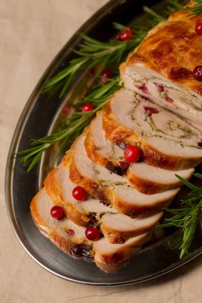 Christmas roll of turkey fillet stuffed with mushrooms and cheese with cranberries and rosemary
