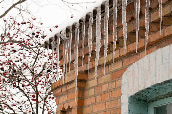 Icicles hanging from the roof of the house. Winter danger