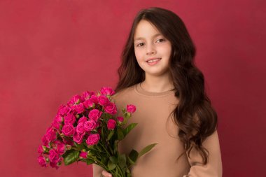 Pembe arka planda bir buket küçük pembe gülle güzel siyah saçlı kız.