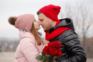 Bir adam genç bir bayana bir buket kırmızı gül verir. Sevgililer Günü konsepti