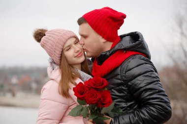 Bir adam genç bir bayana bir buket kırmızı gül verir. Sevgililer Günü konsepti