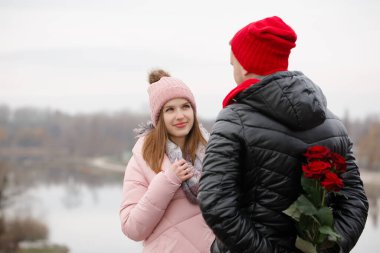 Bir adam genç bir bayana bir buket kırmızı gül verir. Sevgililer Günü konsepti