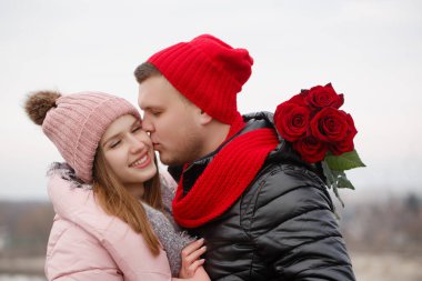 Bir adam genç bir bayana bir buket kırmızı gül verir. Sevgililer Günü konsepti