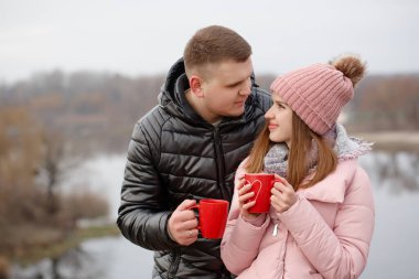 Genç çift nehir kenarında sıcak bir şeyler içiyor. Sevgililer Günü konsepti