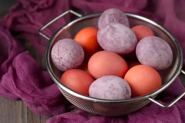 Still life of beautiful textured purple eggs on purple gauze with spring flowers