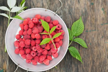 Olgun ahududu, eski ahşap bir arka planda eski bir elek.
