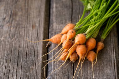 Tahta arka planda yeşil yapraklı sulu yuvarlak havuç.