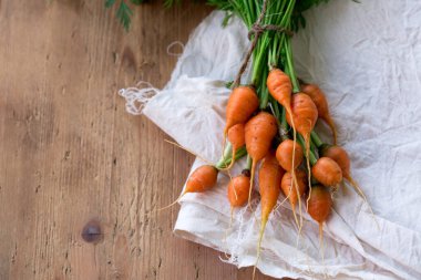 Tahta arka planda yeşil yapraklı sulu yuvarlak havuç.