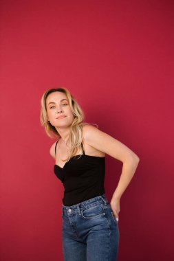 Burgundy arka planda siyah ceketli güzel bir sarışının portresi.