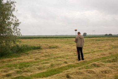 Erkek bir araştırmacı açık alanda bir GNSS alıcısıyla çalışıyor.