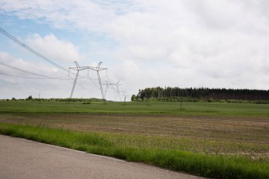 Güneşli bir günde, tarlada yüksek voltajlı elektrik hattı