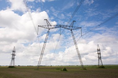 Güneşli bir günde, tarlada yüksek voltajlı elektrik hattı