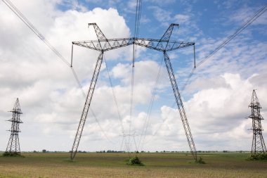 Güneşli bir günde, tarlada yüksek voltajlı elektrik hattı